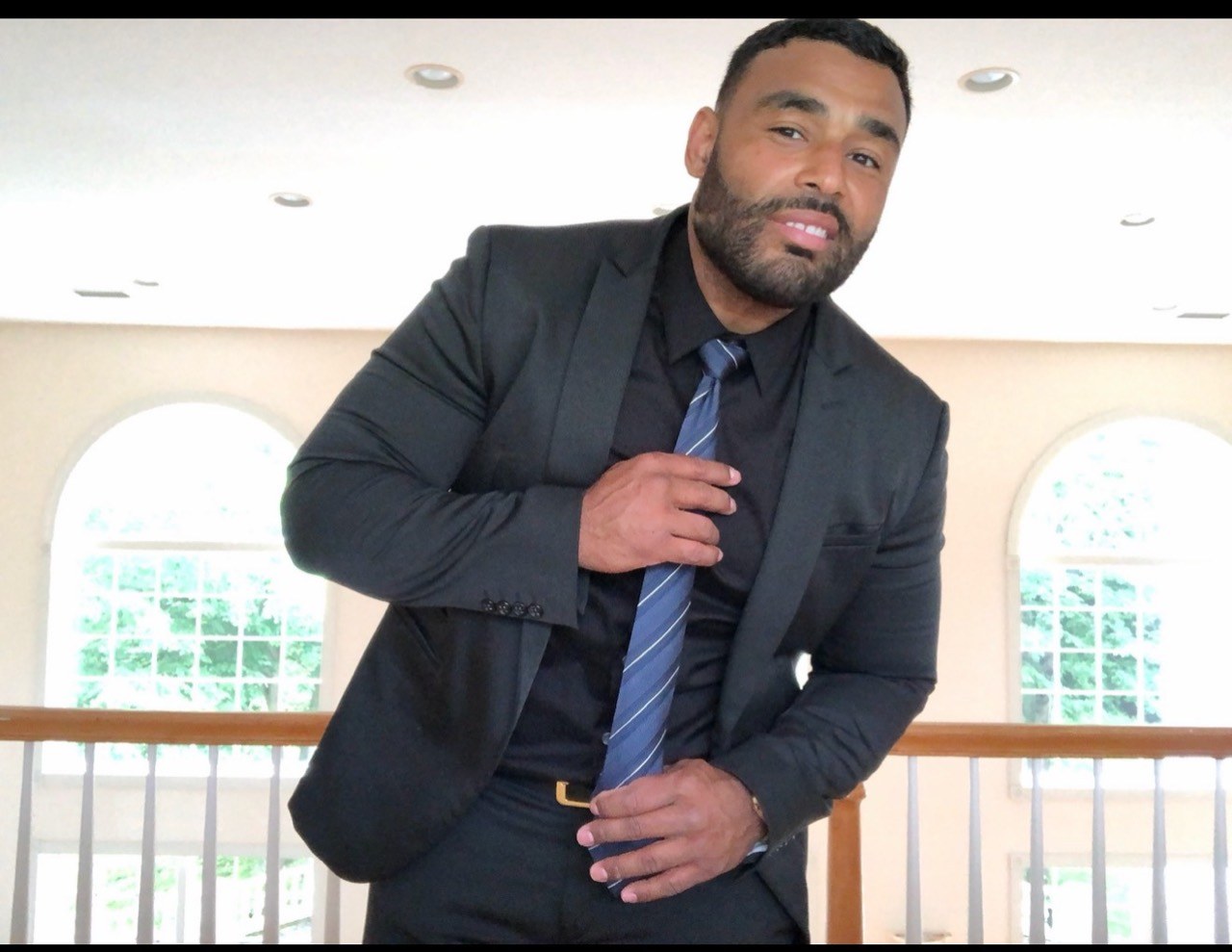 Frank Smith III adjusting his tie while wearing a dark suit