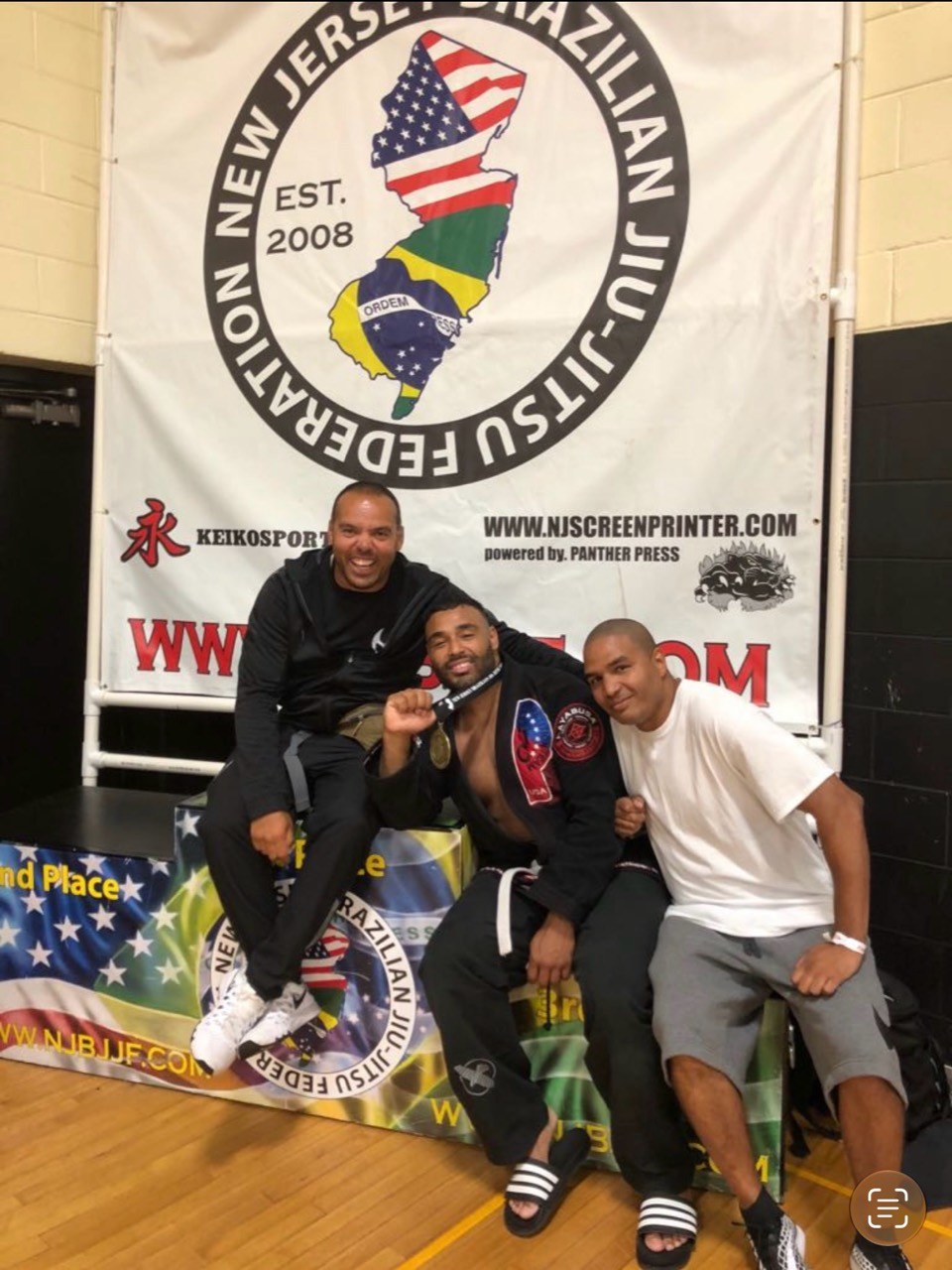Frank Smith III wearing a gi and medal with two companions