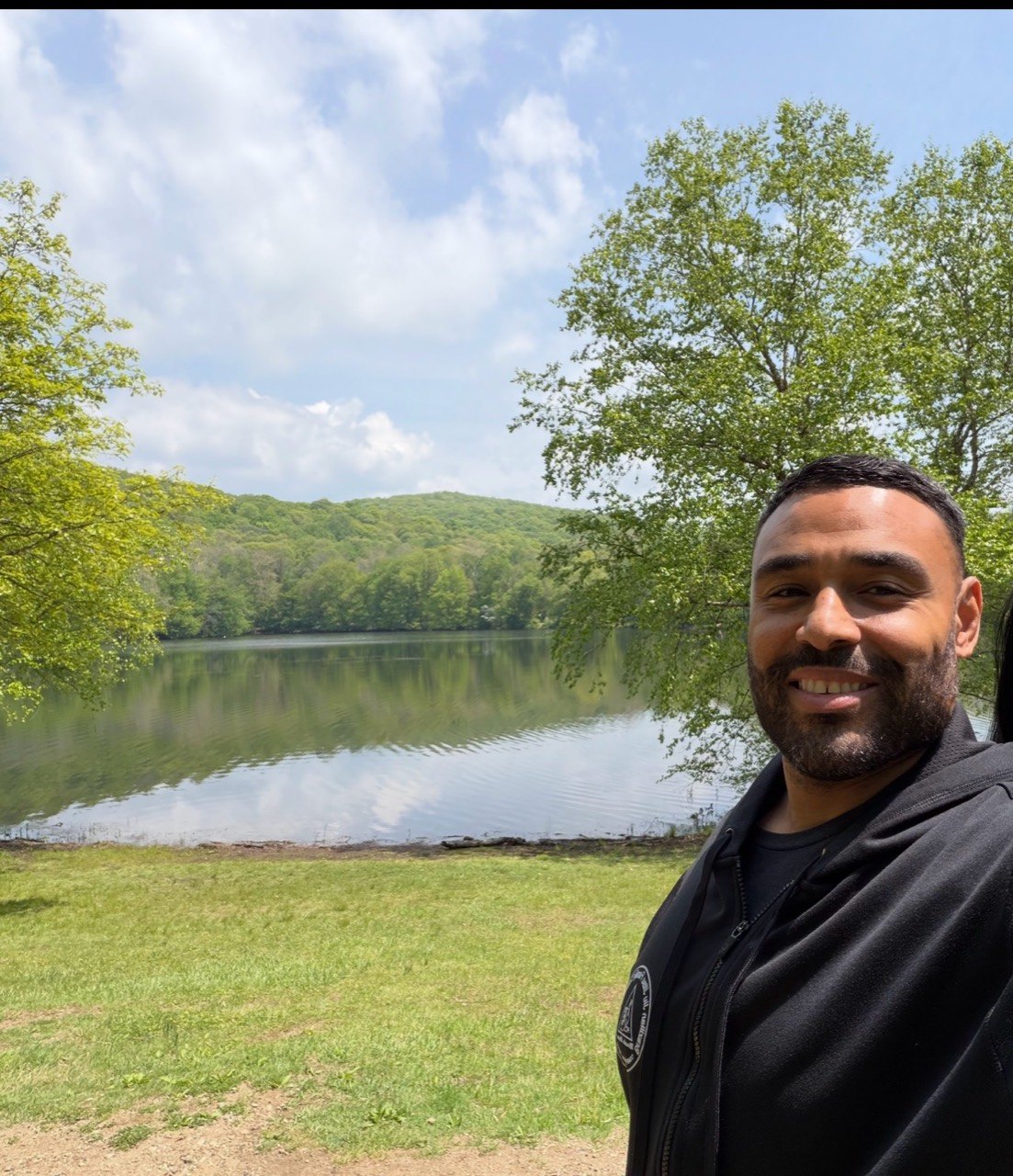 Frank Smith III outdoors near a lake and tree-covered hills