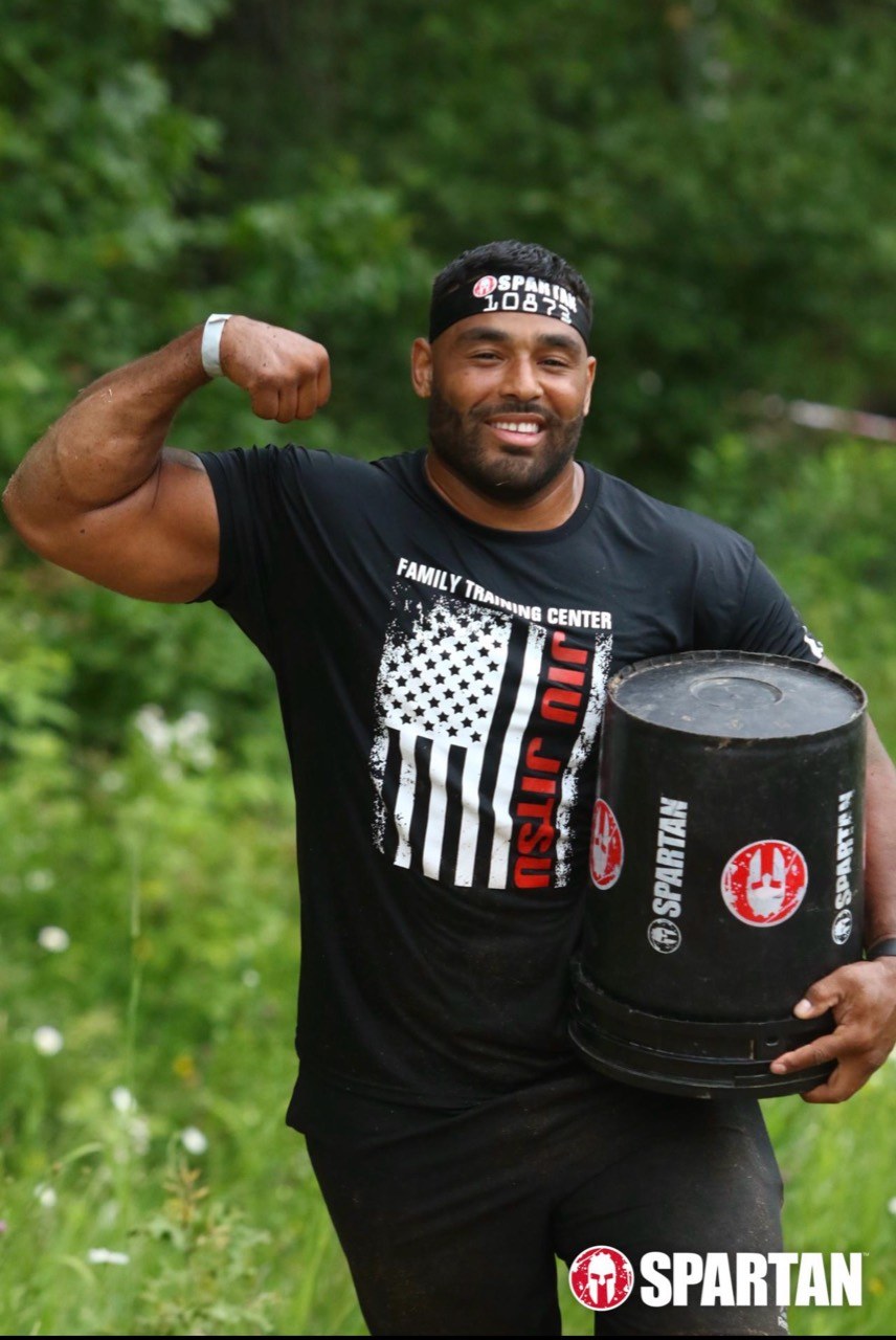 Frank Smith III carrying a Spartan obstacle bucket outdoors