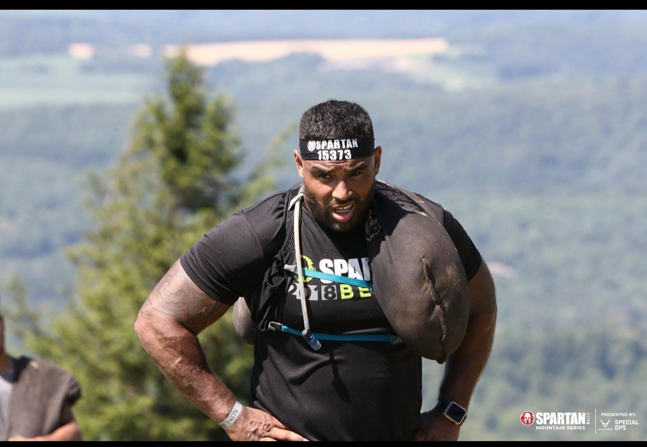 Frank Smith III carrying a weighted bag on a mountain course