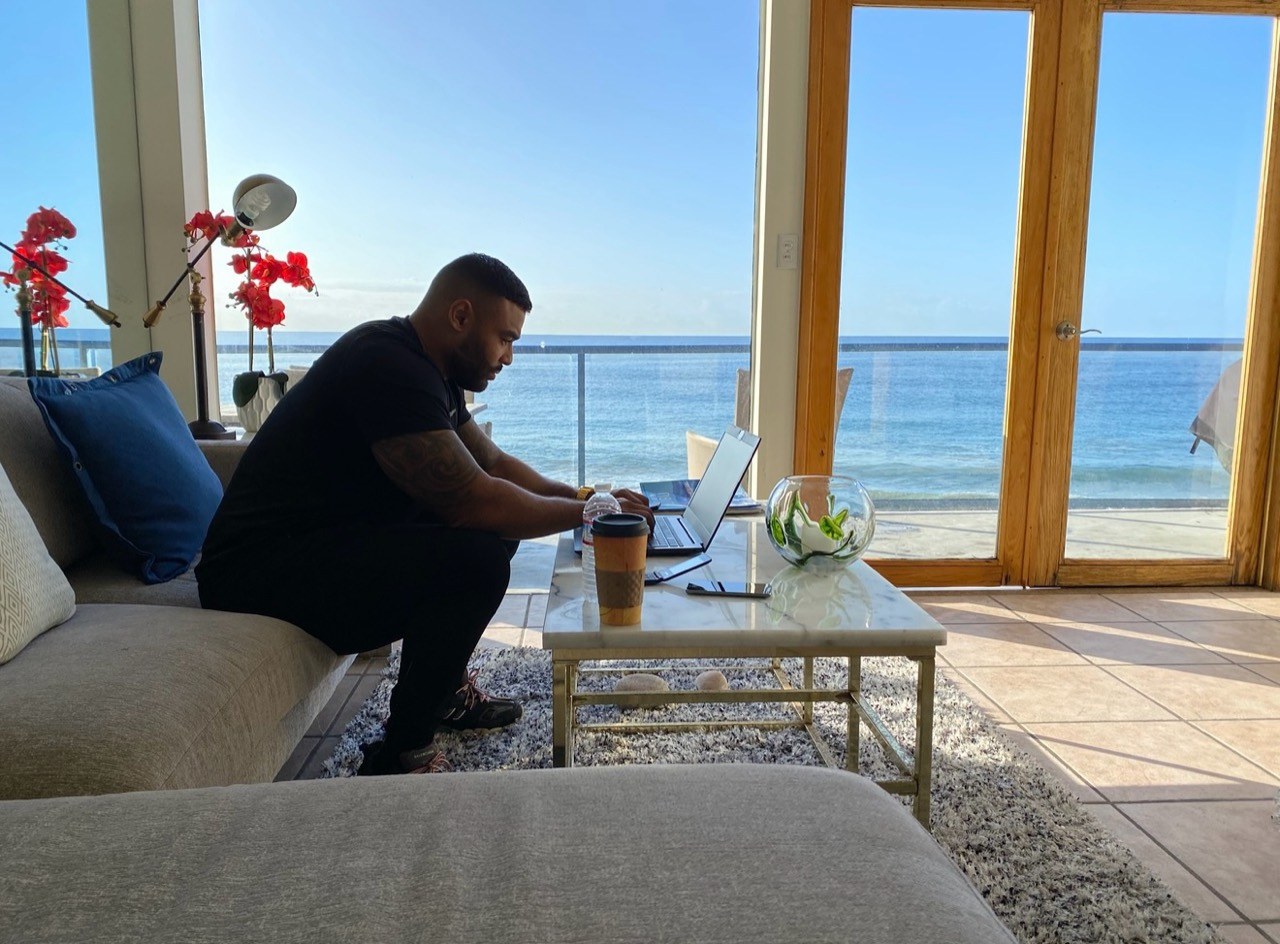 Frank Smith III working on a laptop beside ocean-facing windows