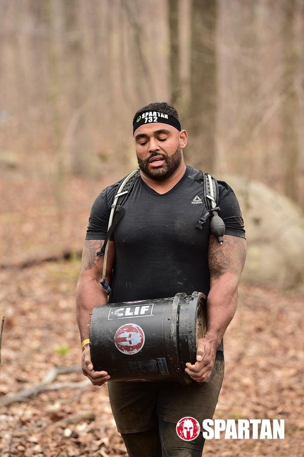 Frank Smith III carrying a bucket during a Spartan race